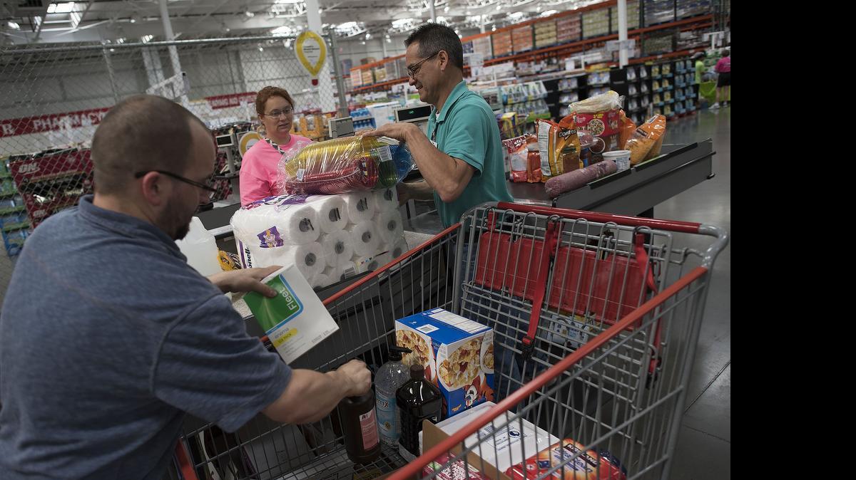 
Employees load a customers purchases into a shopping cart at a Costco Wholesale Corp. store.
