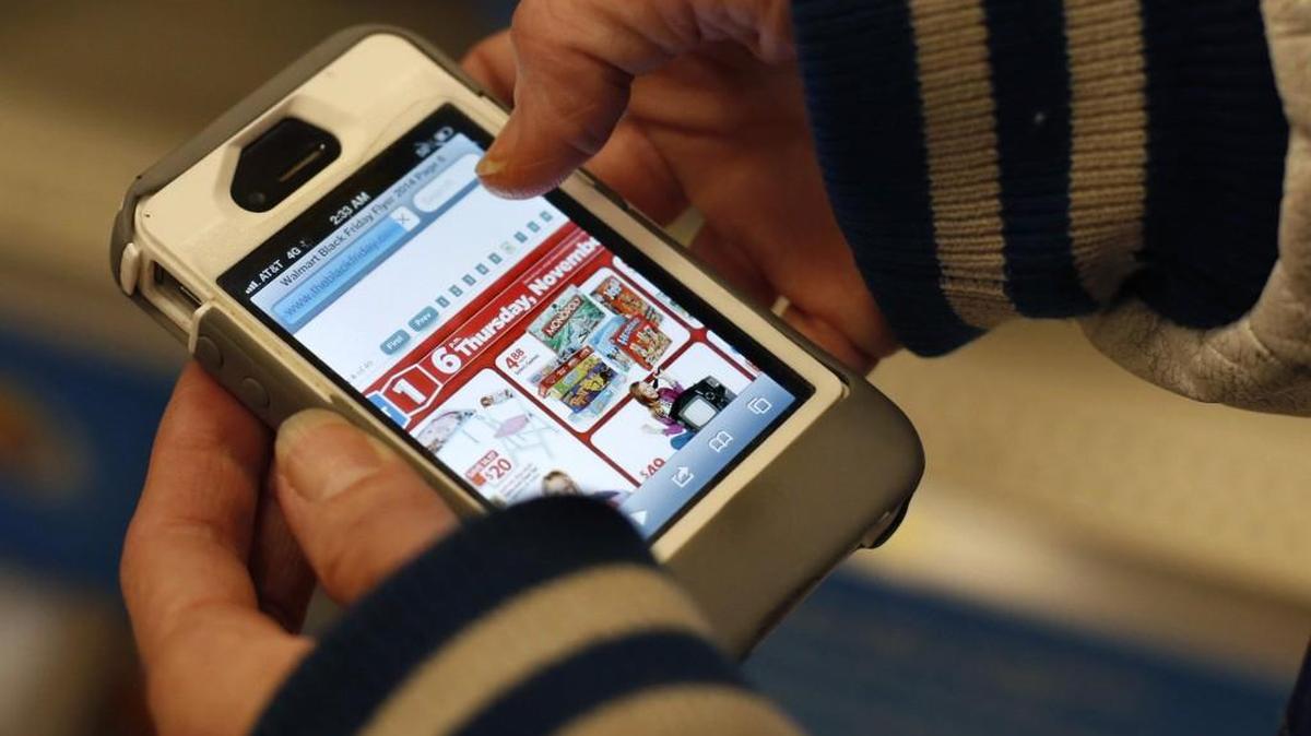 A shopper uses her iPhone to compare prices at Wal-Mart