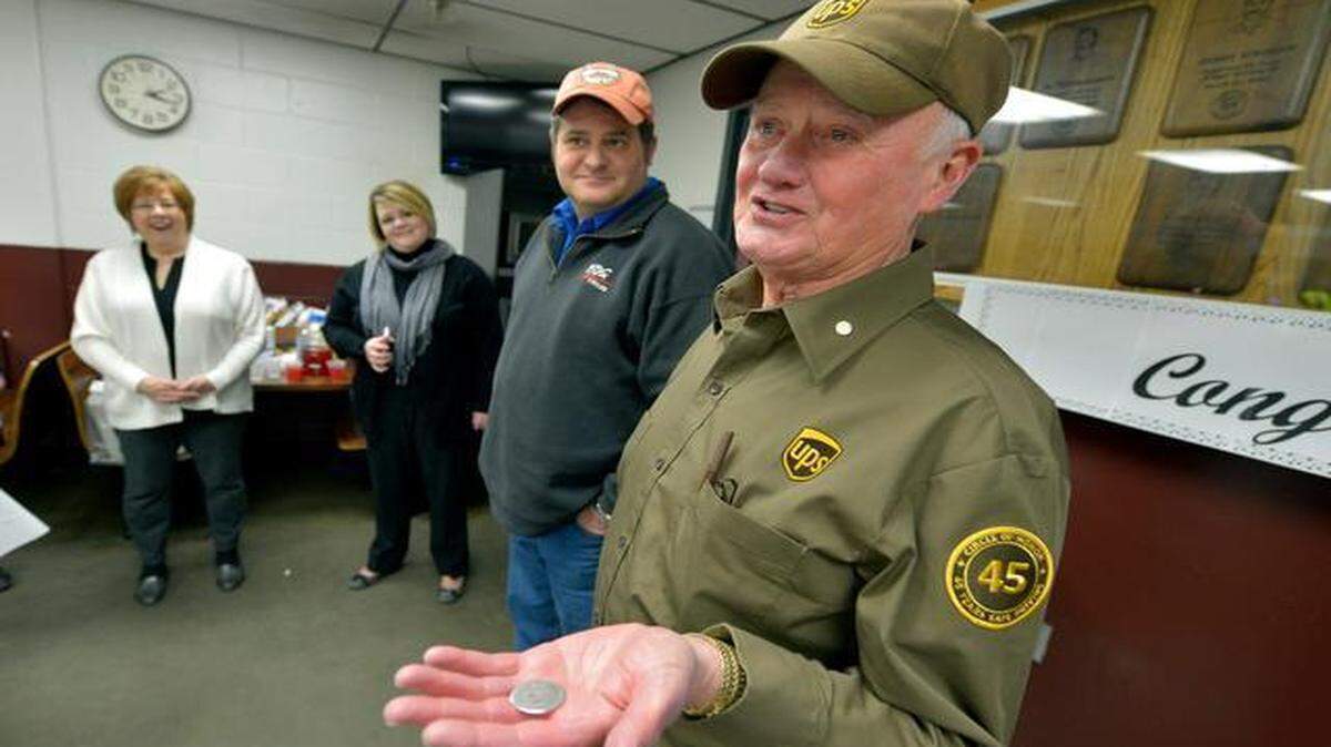 
UPS driver Larry Saunders was honored during a reception Thursday for achieving a remarkable safe driving milestone of 45 years and more than 3 million miles of accident-free driving. Here Saunders displayed his good luck charm, a Kennedy half-dollar coin he got in 1966 when he joined the Air Force. His children, Jim Saunders (second from right) and Angela Currey (third from right), joined him at the reception at the UPS center at 14650 Sante Fe Trail Drive.
