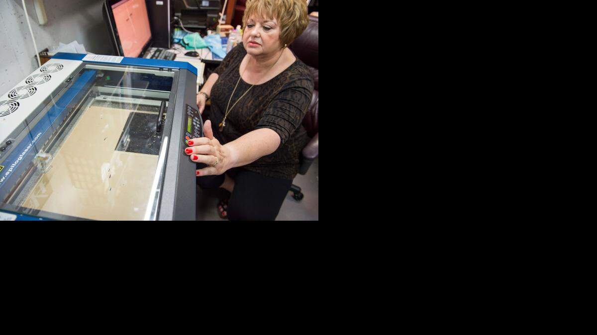 
Janie Hainline readies a laser cutter at Logo Lighthouse, the decorative lighting business she and her husband started in the basement of their Overland Park home.
