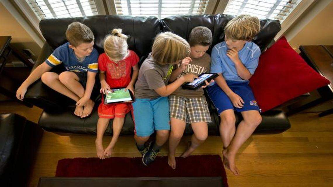 Digital devices <137>Tablets and iPads <137>are a strong draw for friends Kingston Savich (from left), 6; Mia Sutton, 7; Matthew Sutton, 9; Jackson Savich, 9; and Jackson Sutton, 11, who greeted with a cheer news that this week all Shawnee Mission students would be issued laptops or tablets. <137>into the classroom this year. They were at the Savich home in Overland Park on Friday, Aug. 8, 2014.<137>