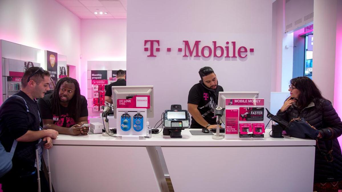 Employees assist customers at a T-Mobile US store in New York.