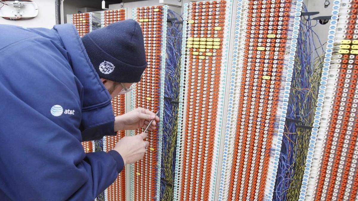 An AT&T cable technician makes a connection at a phone cross box that brings the fiberoptic signal into the phone service box. AT&T plans to roll out faster-speed fiberoptic Internet access to 38 additional cities in 20 states, part of a commitment made to regulators to gain approval for its acquisition of DirecTV.