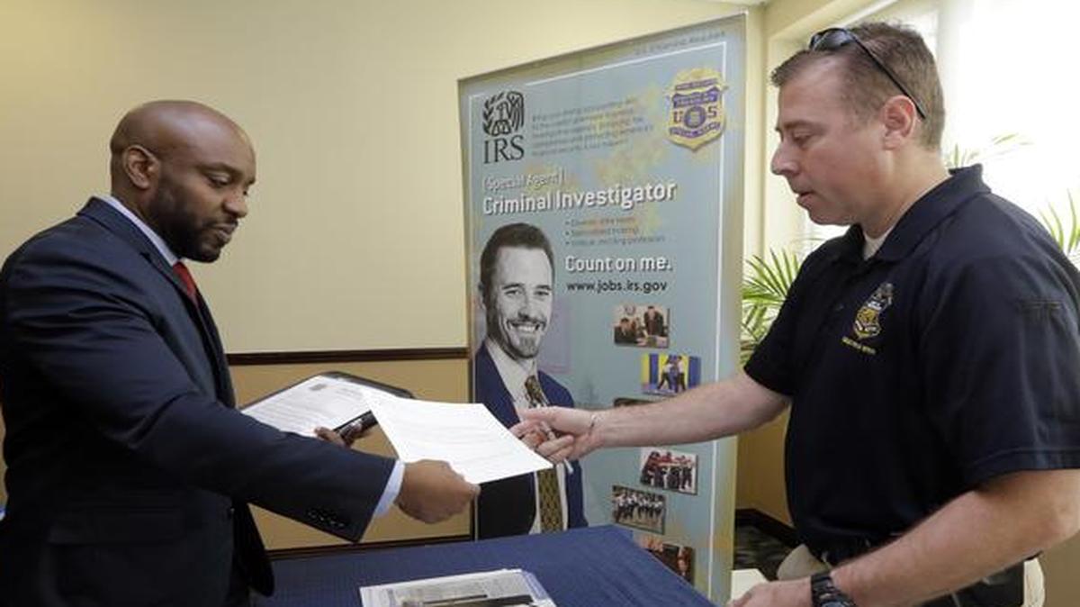 
U.S. Marine Corps Veteran Arlington Robertson, of Fort Lauderdale, left, hands his resume to an Internal Revenue Service Special Agent
