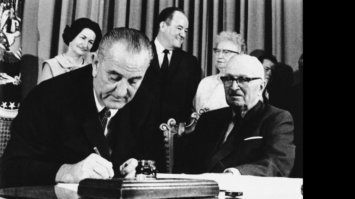
President Lyndon Johnson signs Medicare into law with former President Harry S. Trumanduring a ceremony at the Truman Library in Independence. At rear are Lady Bird Johnson, Vice President Hubert Humphrey and former first lady Bess Truman. When Johnson signed Medicare and Medicaid into law, Americans 65 and older were the age group least likely to have health insurance.
