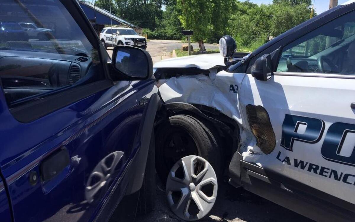 A Lawrence police officer was injured Tuesday morning when his patrol vehicle was hit by another vehicle at the scene of a previous wreck.