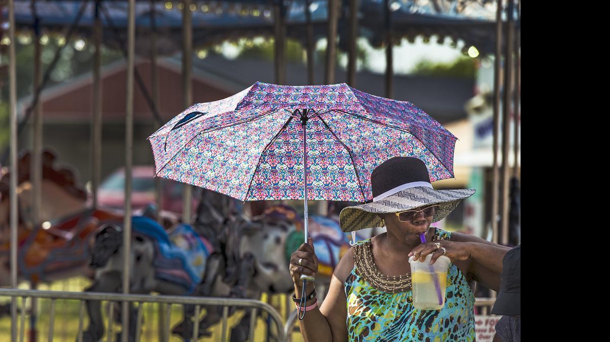 Theresa Lee, of Leavenworth, carried her own shade while taking a sip of lemonade on Friday, July 24, 2015, at the Wyandotte County Fair in Kansas City, Kansas.