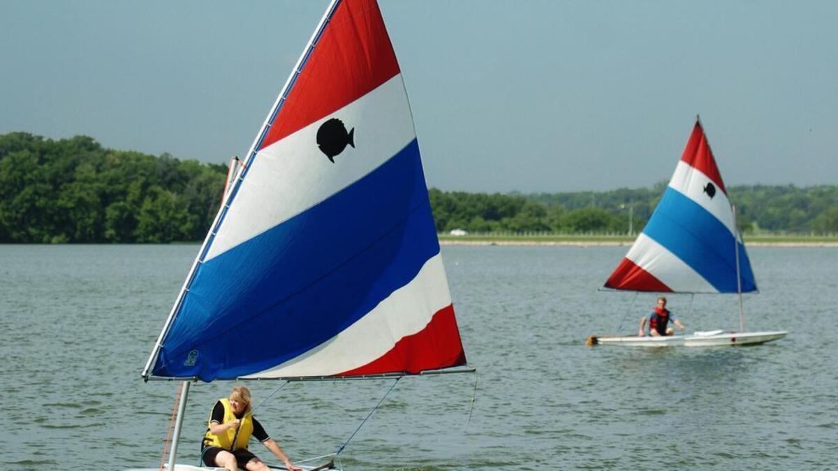 
Fans of sailing like to take to the waves at the area’s many lakes. Shawnee Mission Park Lake is a favorite for some because it doesn’t allow motorboats, which can cause wakes that disrupt the smaller sailboats. On the final day recently of their Sailboat 1 class at Shawnee Mission Park Marina, sailing students Beth Bock (left) of Lenexa and John Colfax of Shawnee operate Sunfish sailboats. The class is given by the Johnson County Sailing Society.
