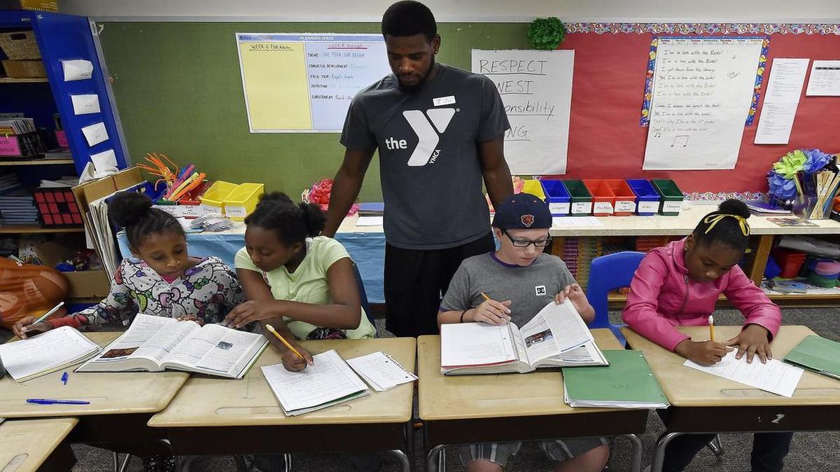 
Instructor Justin Greene (middle) checks the work of a group of fifth graders, who were recently attending a summer school class at Indian Creek Elementary School. Selected students from throughout the Center School District can participate in an expansively long summer school program organized by the YMCA, which also earned the federal grants and other support for the program.

