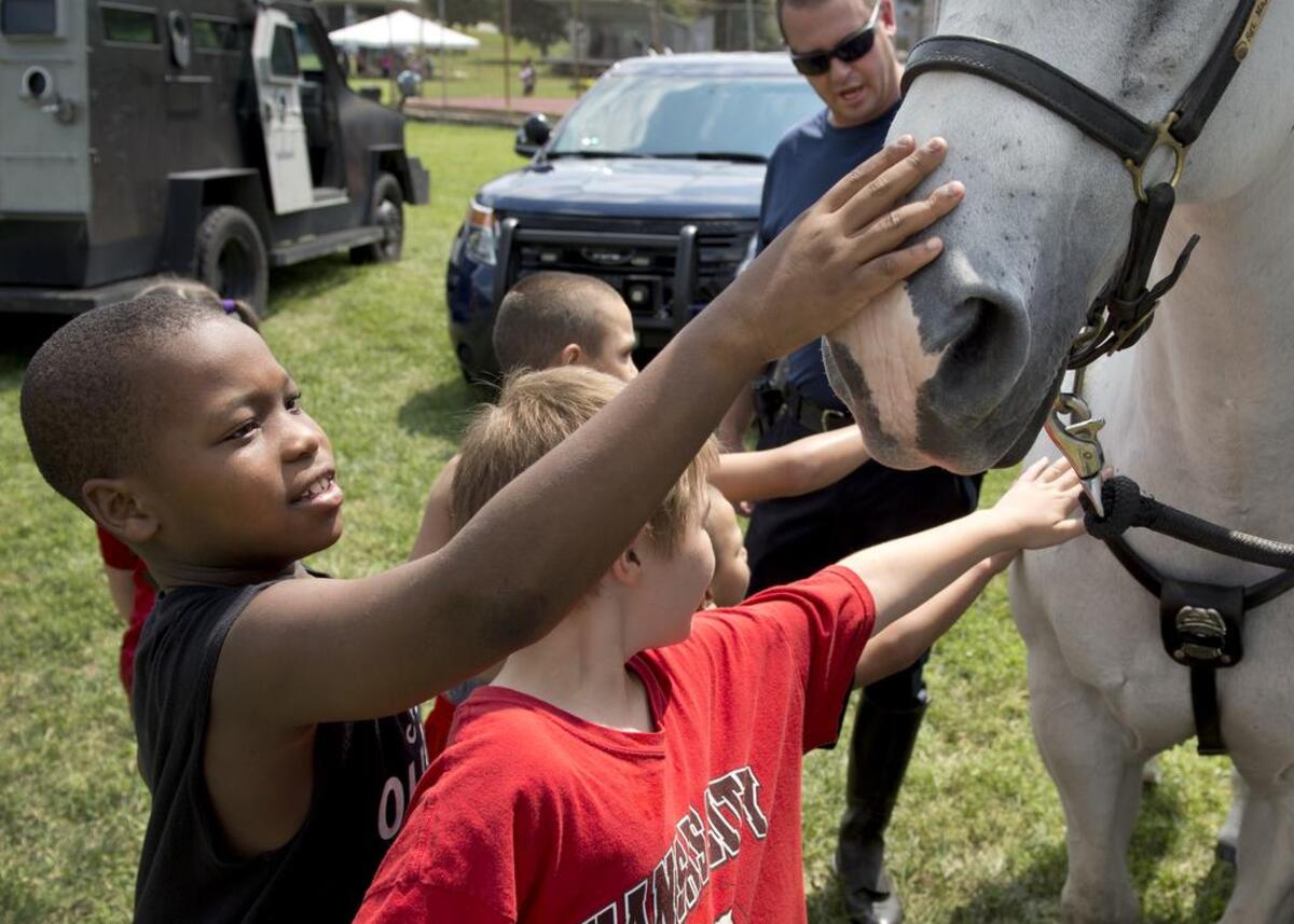 The 12th annual Family Day Against Violence featured games, food, music, dance and swimming on Saturday, Aug. 22, 2015, in Ashland Park at 23rd Street and Cypress Avenue. Lyzjhon Riley (left), 9, and other youngsters petted “Dan,” one of the Kansas City Police Department’s mounted patrol horses.