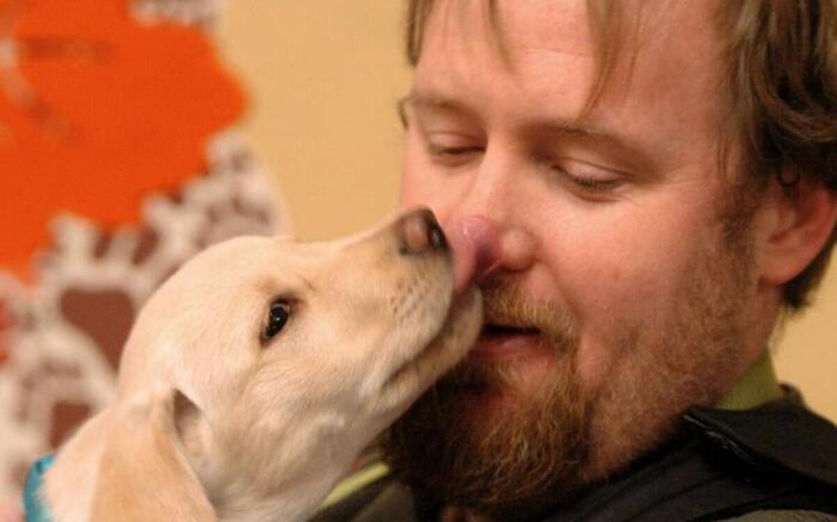 Chris Chancy of Shawnee earned a kiss for adopting a yellow Labrador puppy on Saturday morning at Great Plains SPCA in Merriam.
