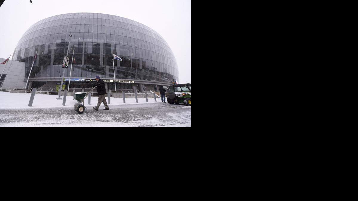 Rod Wagner an employee of the Sprint Center treats the sidewalk outside of the Sprint Center as snow falls in downtown Kansas City on Wednesday.