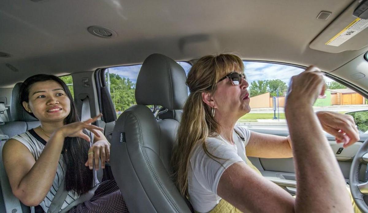 The Rev. Debbie Buchholz signs with Sin Sin, a deaf refugee from Myanmar, while driving her to an American Sign Language class in Kansas City, Kan., for deaf refugees. Buchholz, who is hard of hearing herself, runs a program for deaf refugees through her Olathe church.