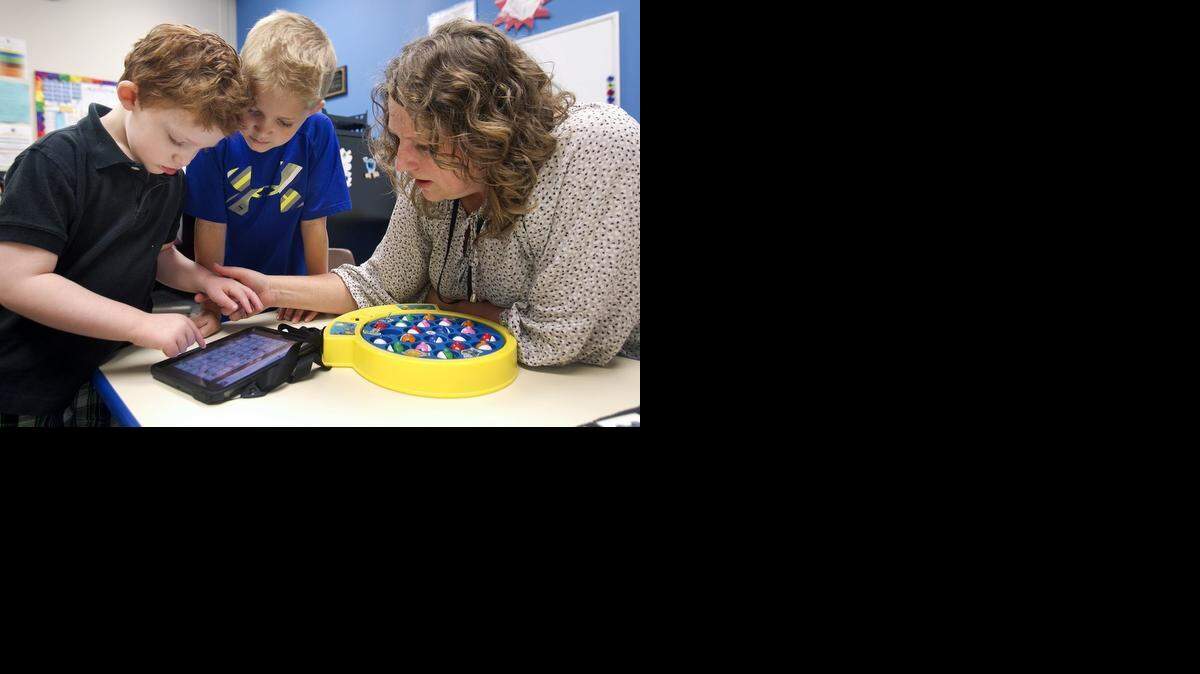 
Carson Stacy, 4, (left) a non-verbal student with autism, gets some help from Park Hill early childhood teacher Elisa Parker (right) in using a computer tablet app to help him communicate. Peer buddy Creed Mattson, 5, is on hand to interact with Carson during the sessions at the Gerner Family Early Education Center in the Park Hill School District.
