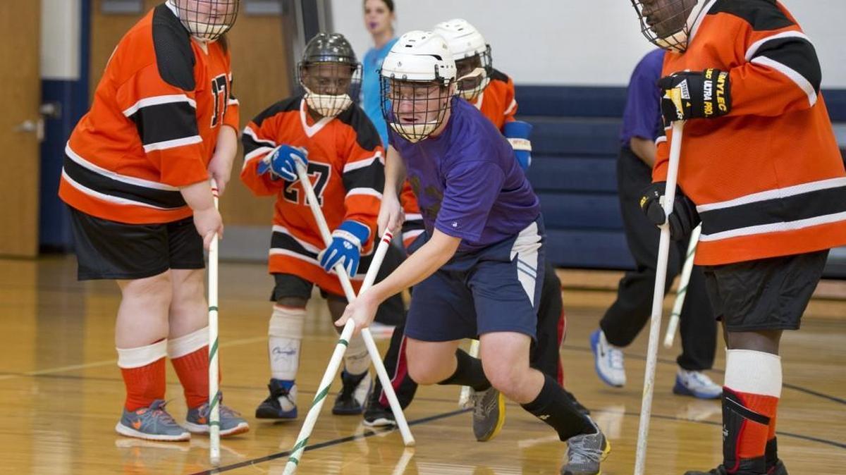 Brandon Schatsiek (center) battled Tiffany Wright (orange team from left), Craig Lovelace and Tom Nelson for control of the puck Sunday during a Special Olympics floor hockey tournament at William Chrisman High School in Independence.