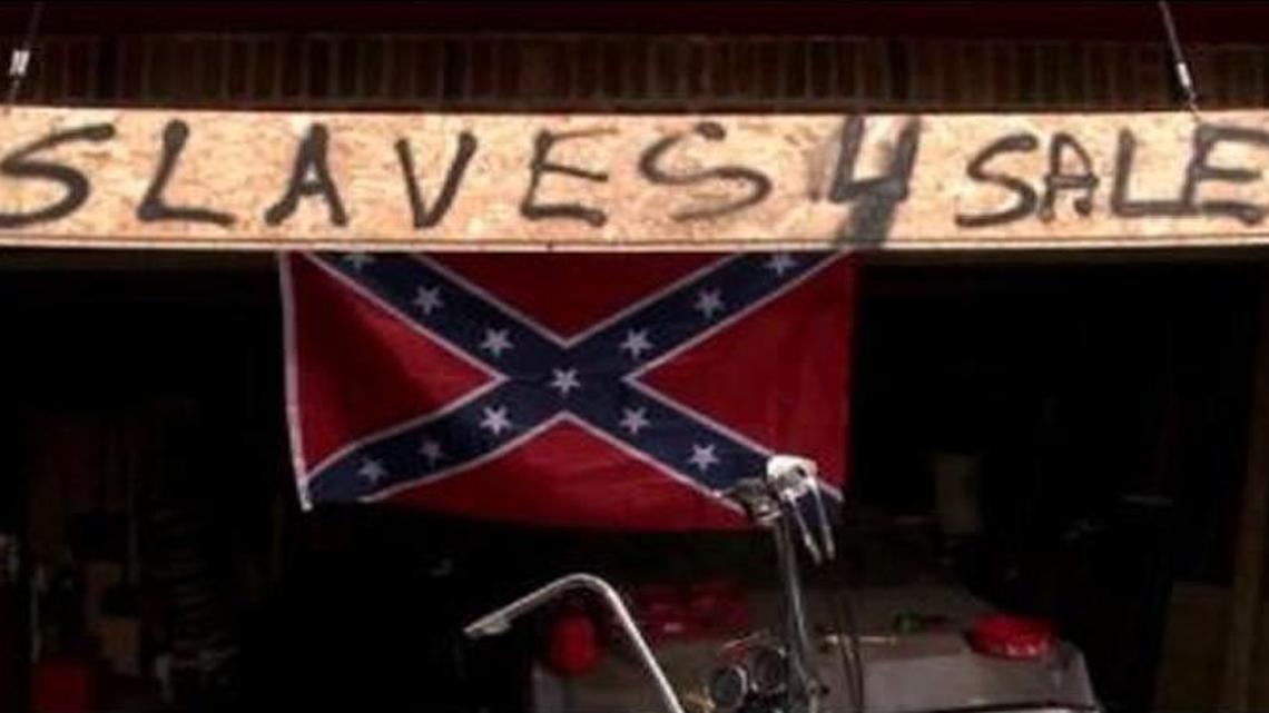A “SLAVES 4 SALE” sign appeared over a Liberty man’s Confederate flag Tuesday.