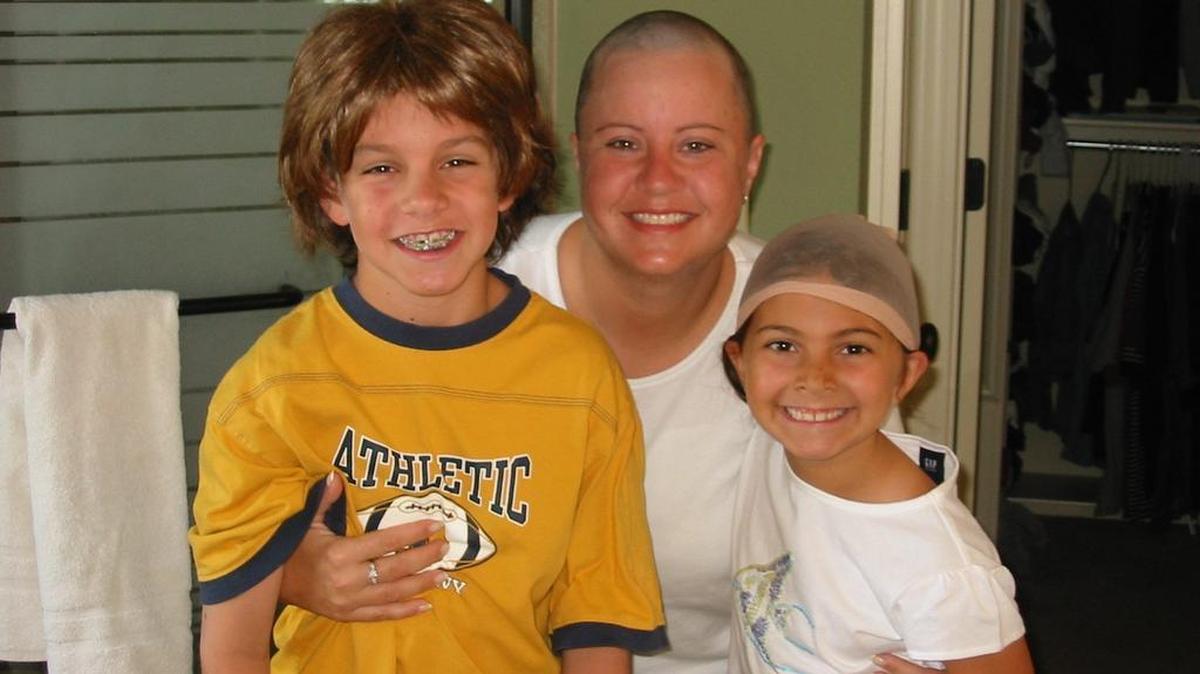 
In 2004, while Kris Campbell was undergoing radiation, she posed with Harrison (age 9) wearing her new wig and Madeleine (age 7) wearing her wig cap. 


