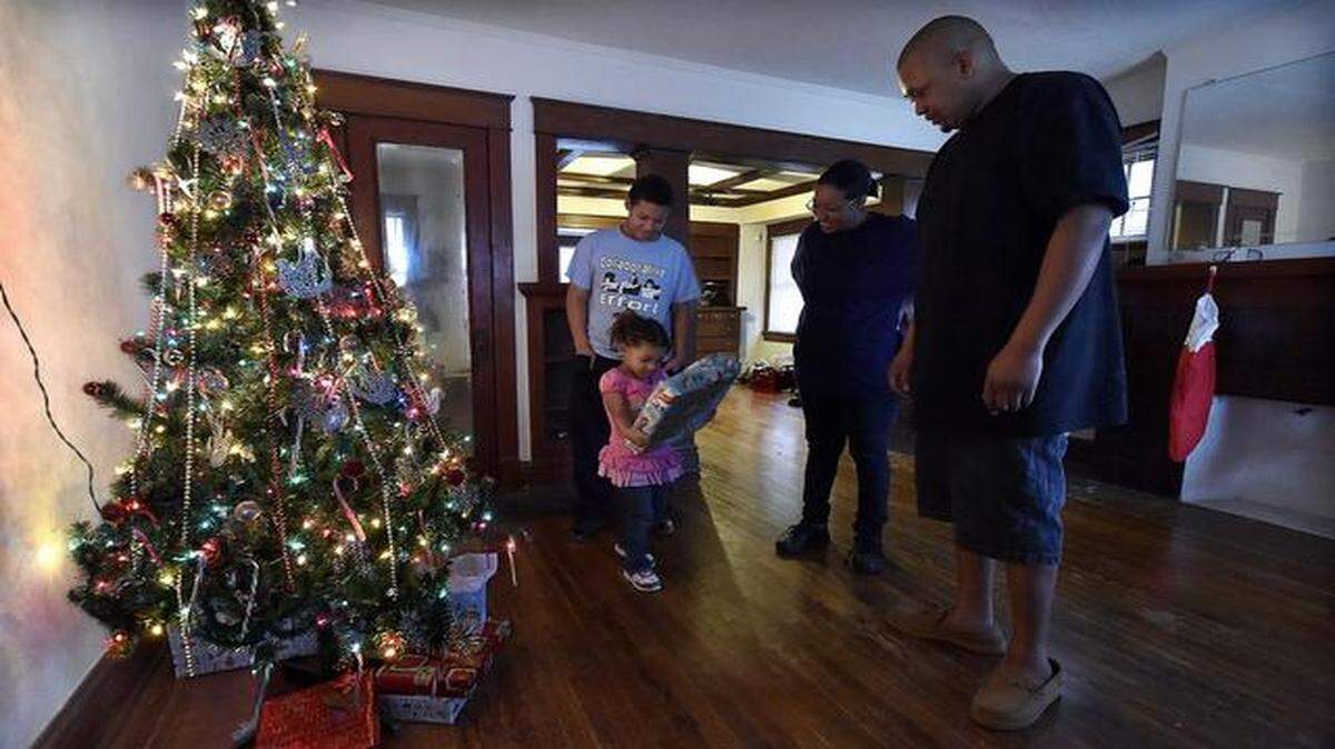 Although their furniture and appliances had not yet arrived, the Ricks family had no problem getting into the holiday spirit after moving into their new home. Tori, 3, was curious what might be inside one of her presents under the tree in the family's living room. She was joined by her brother C.J. 13, and parents, Latoria and Elliott Ricks.
