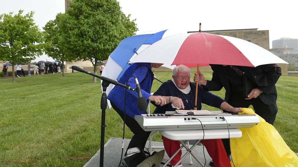 
Keyboardist Bonnie Hanchett wrapped her keyboard to protect it from rain with help from fellow musicians Joyce McHenry (left) and Jim Anderon while they moved to escape the rain Thursday during the National Day of Prayer event at Liberty Memorial. Rain forced the event indoors.
