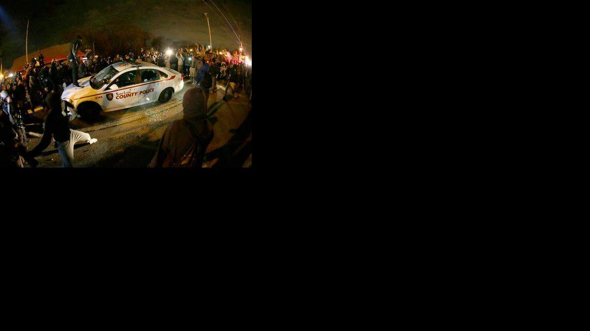 
A protester squirts lighter fluid on a police car as the car windows are shattered near the Ferguson Police Department after the announcement of the grand jury decision not to indict police officer Darren Wilson in the fatal shooting of Michael Brown, an unarmed black 18-year-old.
