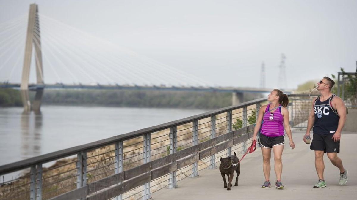 Walking with their dog, Kota, Meg and Clint Helf of Kansas City stop to look at the Heart of America Bridge at Berkley Riverfront Park. In the background looms the Kit Bond Bridge.