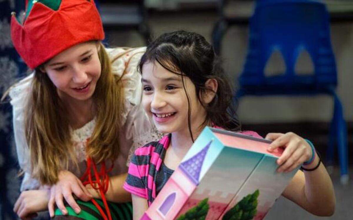 
Emerson Pereira, 11, watched Keylit Gomez, 8, open her gift Monday at the Della Lamb Elementary Charter School in Kansas City. Emerson was one of the actors from the Kansas City Repertory Theatre’s production of “A Christmas Carol” who visited the school and gave holiday gifts to the students.

