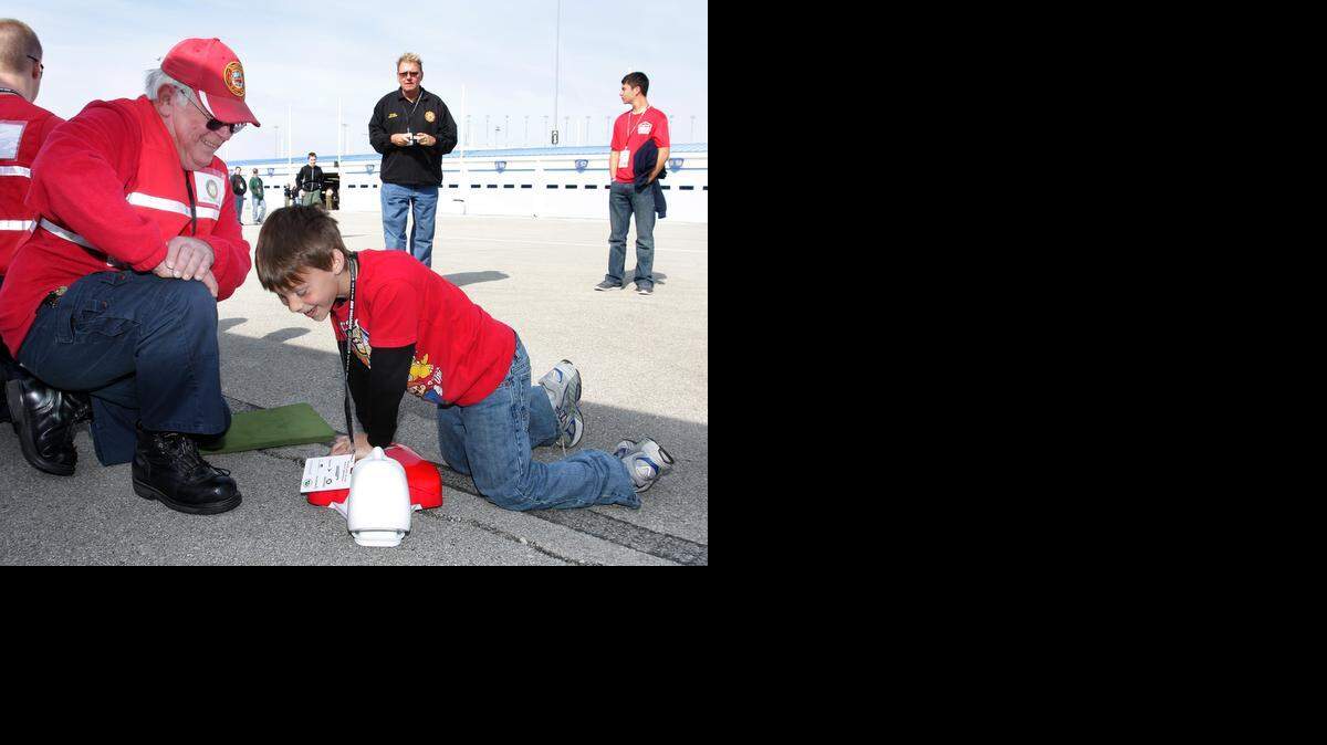 Nicholas Yearout, 9, learned about hands-only CPR on Saturday from Bob Hundson of the Independence Fire Explorers during Scouting 500 at Kansas Speedway.