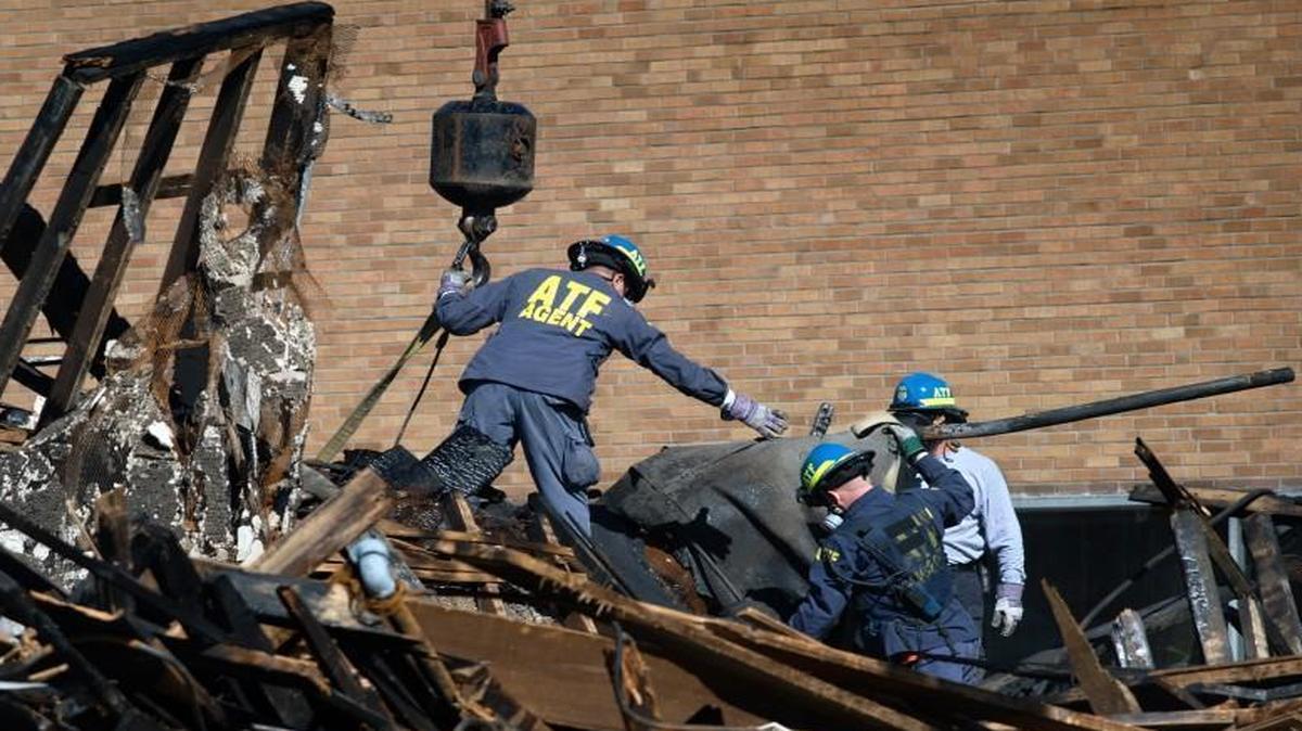 ATF agents connected straps to a crane on Oct. 16 as debris was lifted away from the burned out remains of the building at Independence and Prospect avenues where two firefighters died.