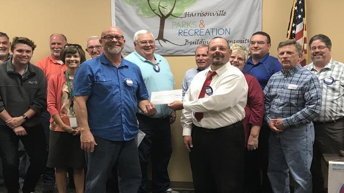 Members of the Harrisonville Rotary Club recently gathered as President Bing Schimmelpfenning (right) presented a check for more than $6,000 to Parks and Recreation Director Chris Deal (left).