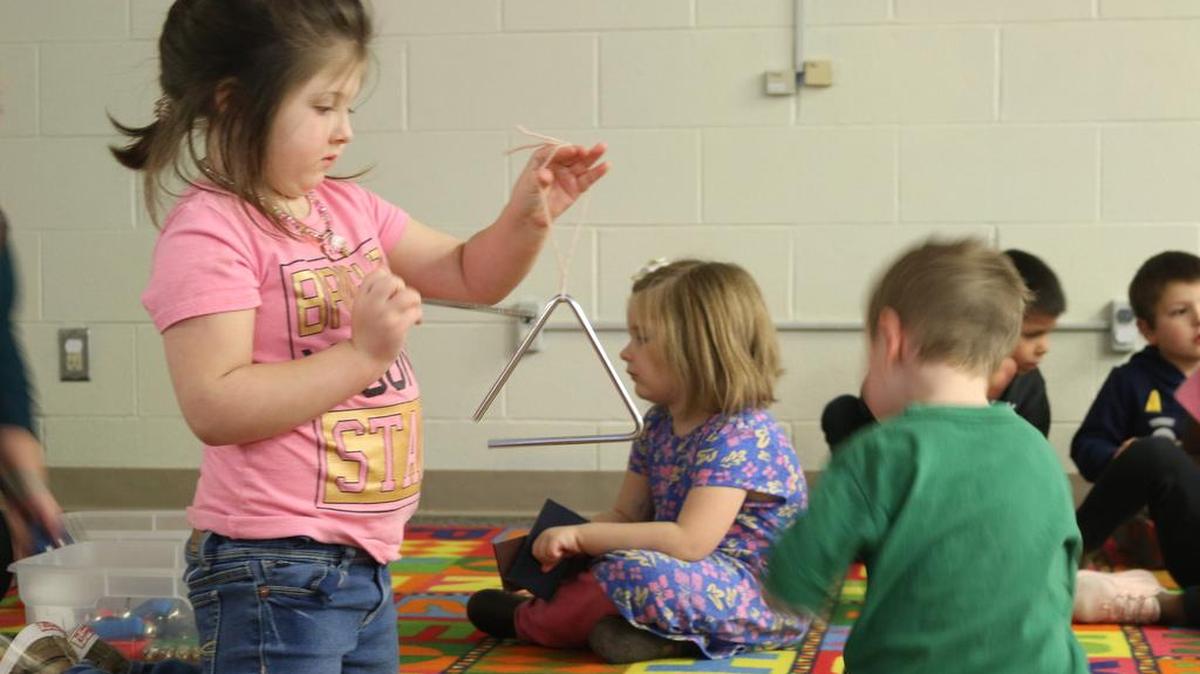 Pre-K student Macinzie Marlow plays the triangle as her classmates scramble to get their own instruments at Shull Early Childhood Center’s Imagination Station.