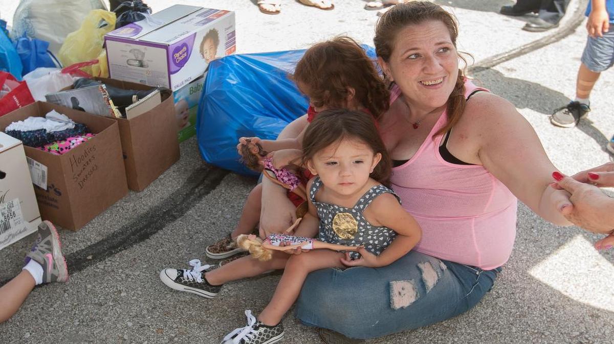
Sarah Robinson and her twin 2-year-olds, Becky and Bellasara (foreground) Aguilar, thanked people who dropped off donations for the mother and her six kids Saturday at the Roeland Park Police Department.
