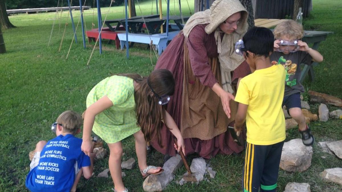 Historic site guide Leslie Nottingham leads children in a limestone cutting demonstration at Mahaffie Stagecoach Stop and Farm.