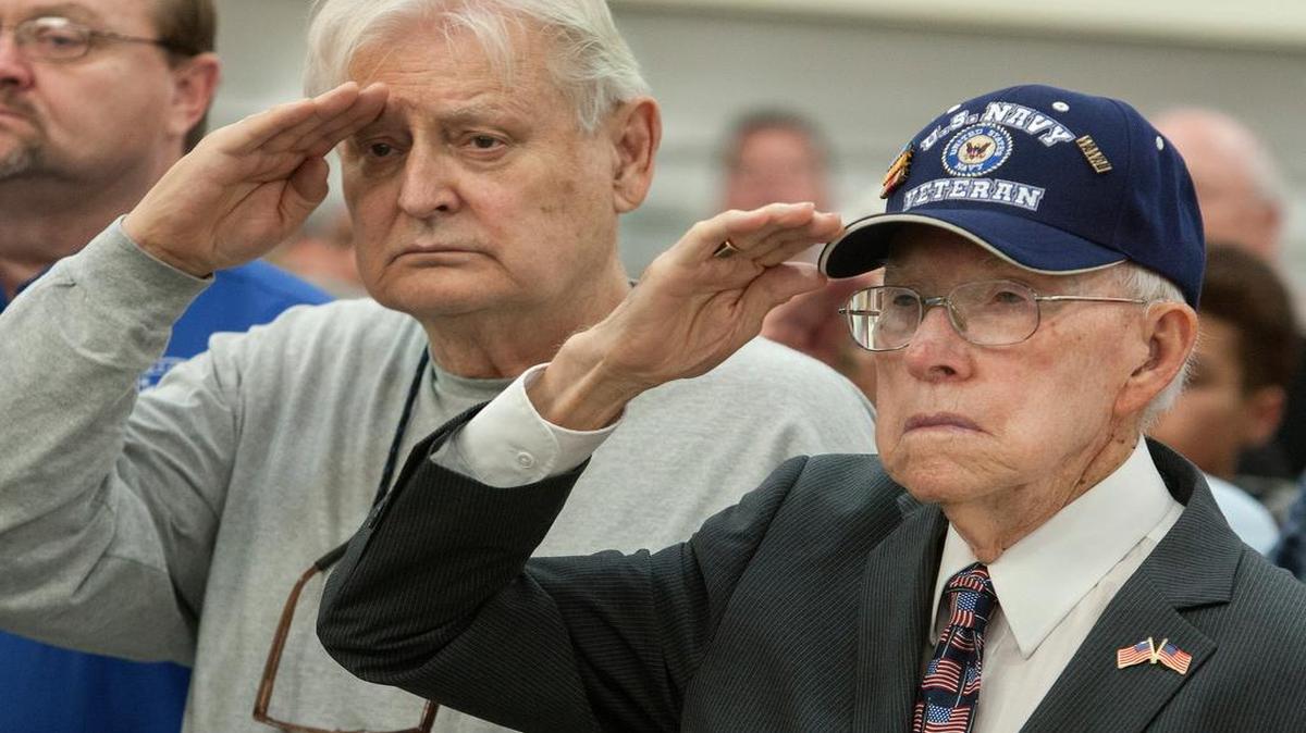 Air Force veteran Harlan Blede of Overland Park (left) and Navy veteran Bob Laskey of Merriam saluted the flag Wednesday at the Veterans Day ceremony in Lenexa.