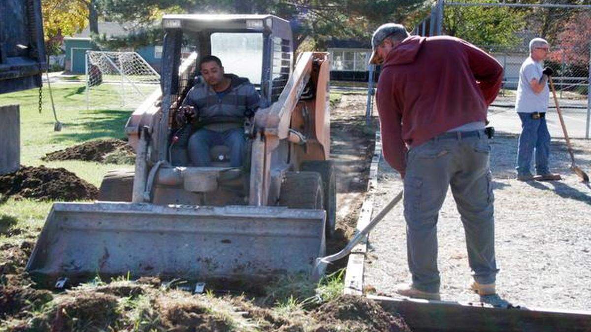 
Mike Rogers scoops dirt with construction equipment as Ismeal Enriquez shovels it out of the trail track.
