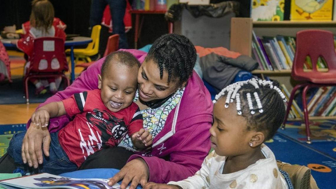 Playing with or reading to children — as Kannie Donnell did with her two children in this 2016 file photo — can be a great way to invest a resource more valuable than money: you time.