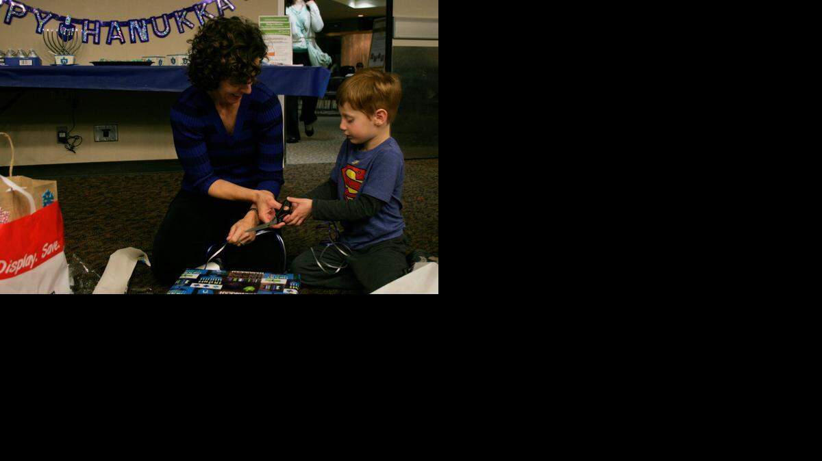 
Beth Sherry of Prairie Village and her 5-year-old son, Gabe, wrapped presents at the Jewish Family Services Hanukkah gift wrapping party. 
