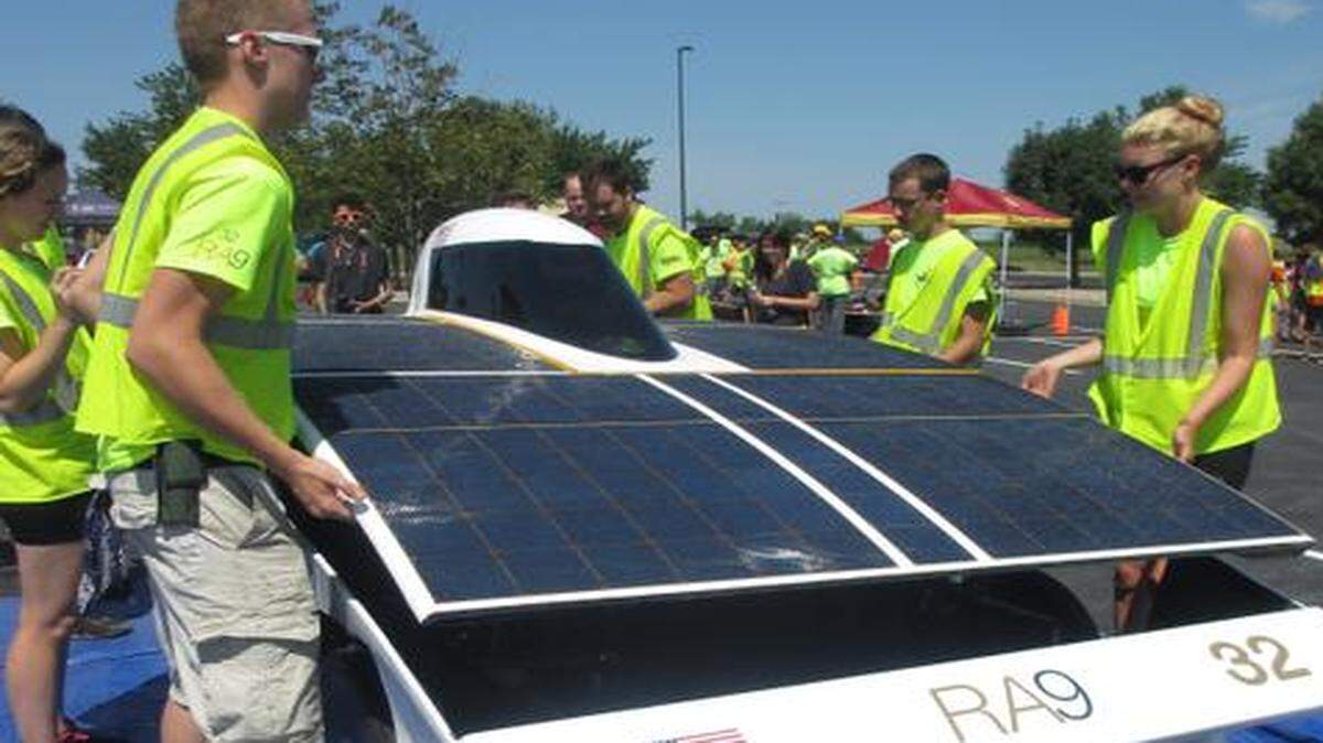 Jackson Walker of Leawood (left) helped his team lift the top of the Principia College solar car.
