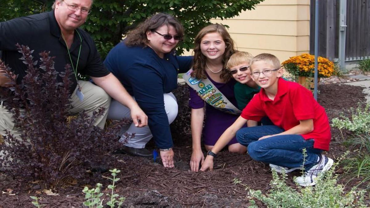 For the cutline: The Jansen family (left to right) Ron, Elaine, Samantha, Matt and Jacob plant flowering bulbs in the Memorial Brick Garden.
