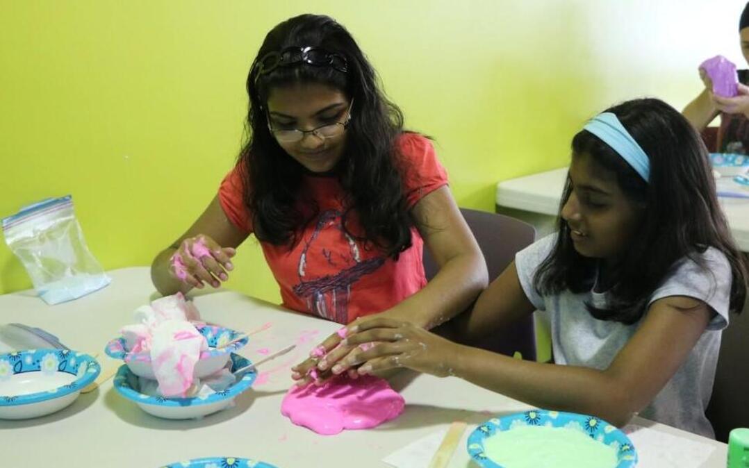 Fast friends and future physicians, Aryn Nair, 11, and Meirah Paul, 12, collaborate on a slime activity during the Olathe STEAM – Slime event held Thursday at the Olathe Teen Commons.