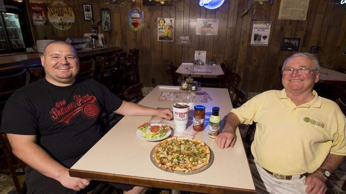 
William Walker and his father, Joe Walker, display a Smoke House specialty pizza, house salad and a couple of jars of their salad dressing at Old Shawnee Pizza. Joe started Old Shawnee Pizza, then called Pizza Shoppe, in 1969.
