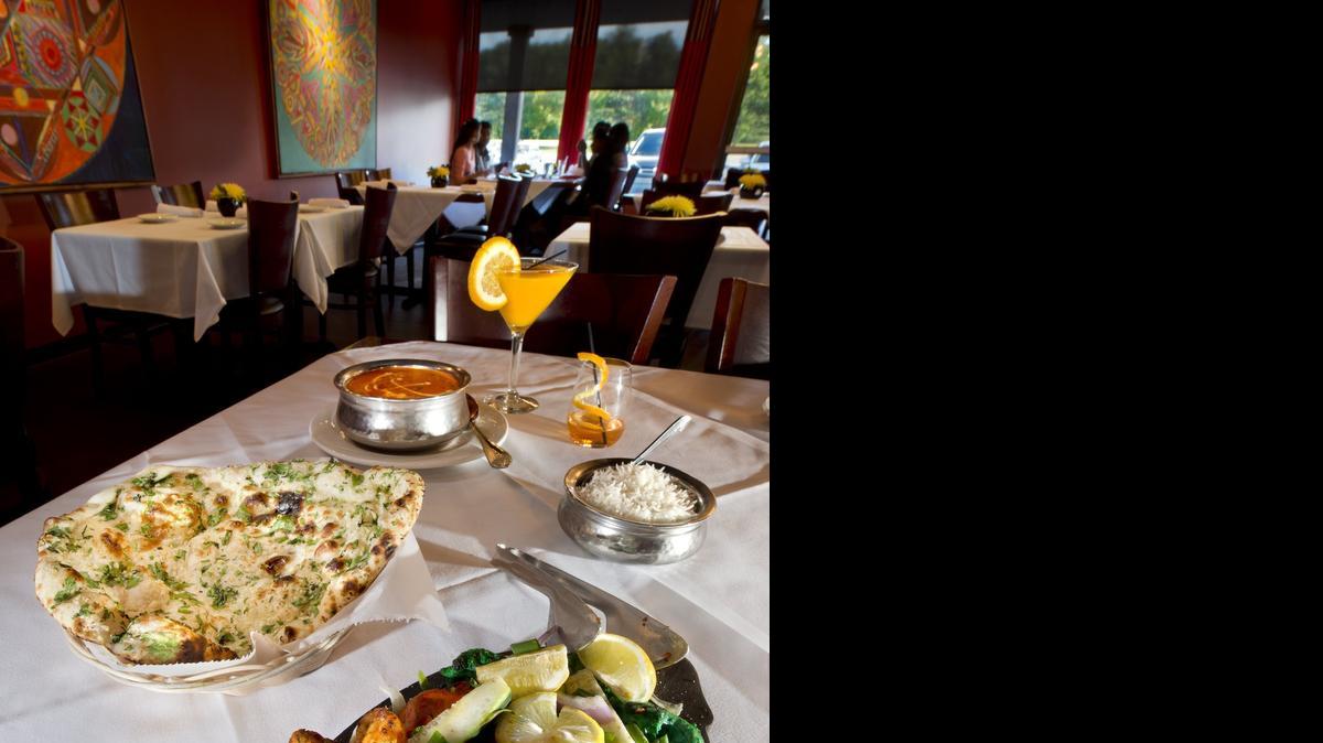
Kulture Kurry serves northern Indian cuisine at 9940 College Blvd. in Overland Park. Among their menu items are the Kansas Krackle (foreground), featuring assorted meats served with rice, sauce, mint and coriander, garlic naan (left) and Chicken Makhani, chicken cooked in a buttery smooth tomato gravy. 
