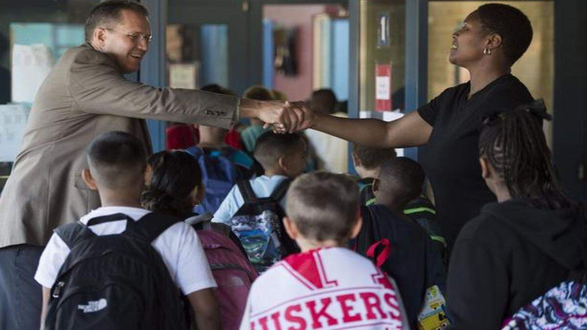 Mike Brewer (left) welcomed students and parents to the first day of school Tuesday at Broken Arrow Elementary School in Shawnee. Brewer is new to the school and the district this year. Mother Nakia Young was dropping off her fourth-grade twins at the school.<252><137>Mike Brewer (left), new principal, shook hands with Nakia Young, of Shawnee, as he welcomed students and parents to the first day of school at Broken Arrow Elementary School, 5901 Alden, on Tuesday, August 12, 2014, in Shawnee, Kansas. Brewer is new to the district and to Broken Arrow this year. He most recently served as the executive director of elementary education in Liberty. Young was dropping off her fourth-grade twins.<252><137>