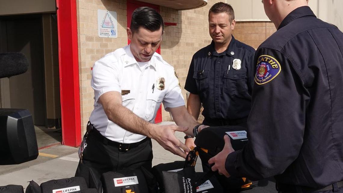 Olathe Fire Department Division Chief Joey Heideman (left) passed out automated external defibrillators to Captain Jake Ring (middle back) and Firefighter Kyle Ledgerwood (right) as part of a collaborative effort with the PulsePoint Foundation.