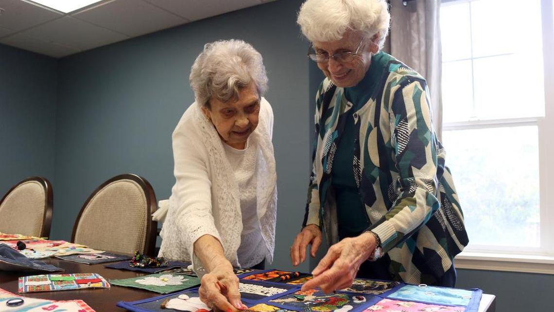 Caroline Summers and Dee Robinson discuss how Robinson made butterfly wings stand up on one of the quilt squares with fabric stiffener.