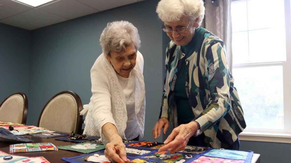 Caroline Summers and Dee Robinson discuss how Robinson made butterfly wings stand up on one of the quilt squares with fabric stiffener.