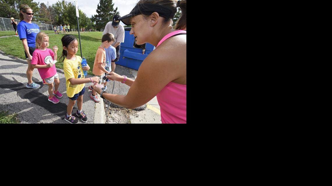 Volunteers Bill Lepping (left, rear) and Janet Schrick (right) recently scanned bar codes to record the distance run by students including Kayla Van Baale (left) and Ashlyn Whitney, both second-graders on the SunRunners Running Team at Sunnyside Elementary School in Olathe.