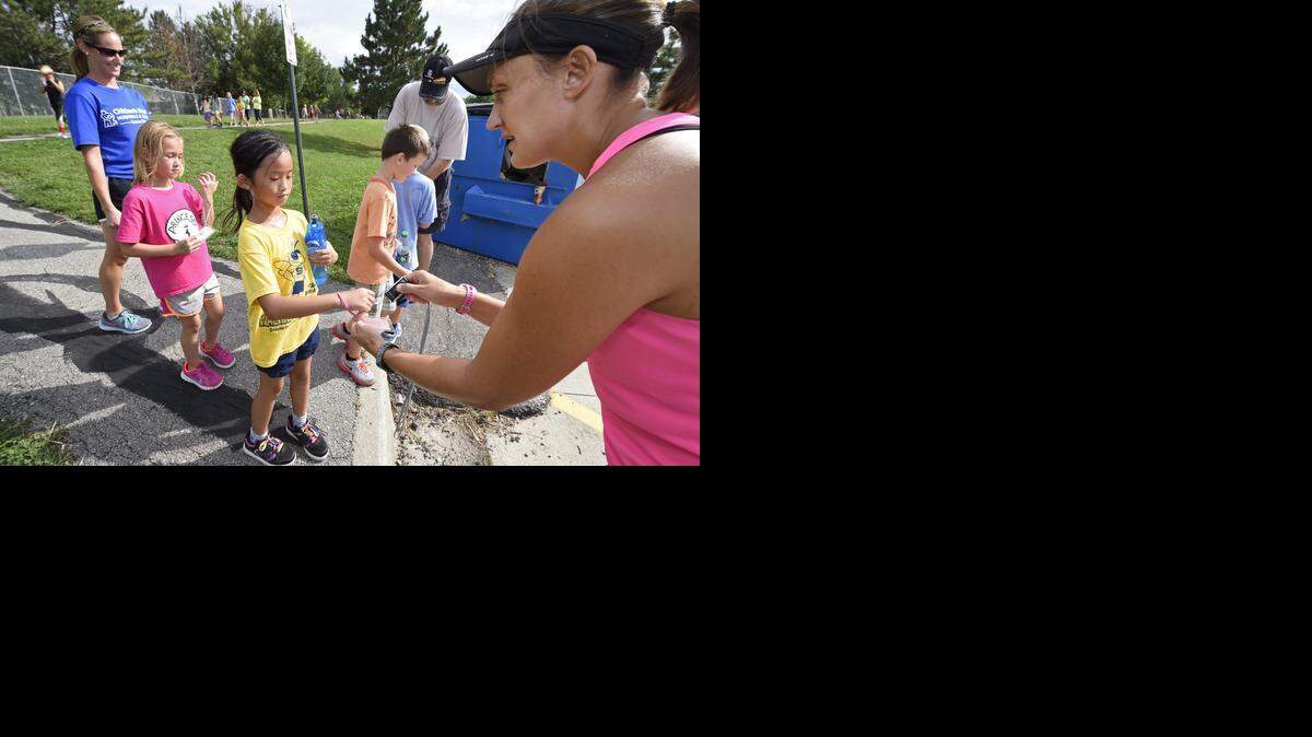 Volunteers Bill Lepping (left, rear) and Janet Schrick (right) recently scanned bar codes to record the distance run by students including Kayla Van Baale (left) and Ashlyn Whitney, both second-graders on the SunRunners Running Team at Sunnyside Elementary School in Olathe.