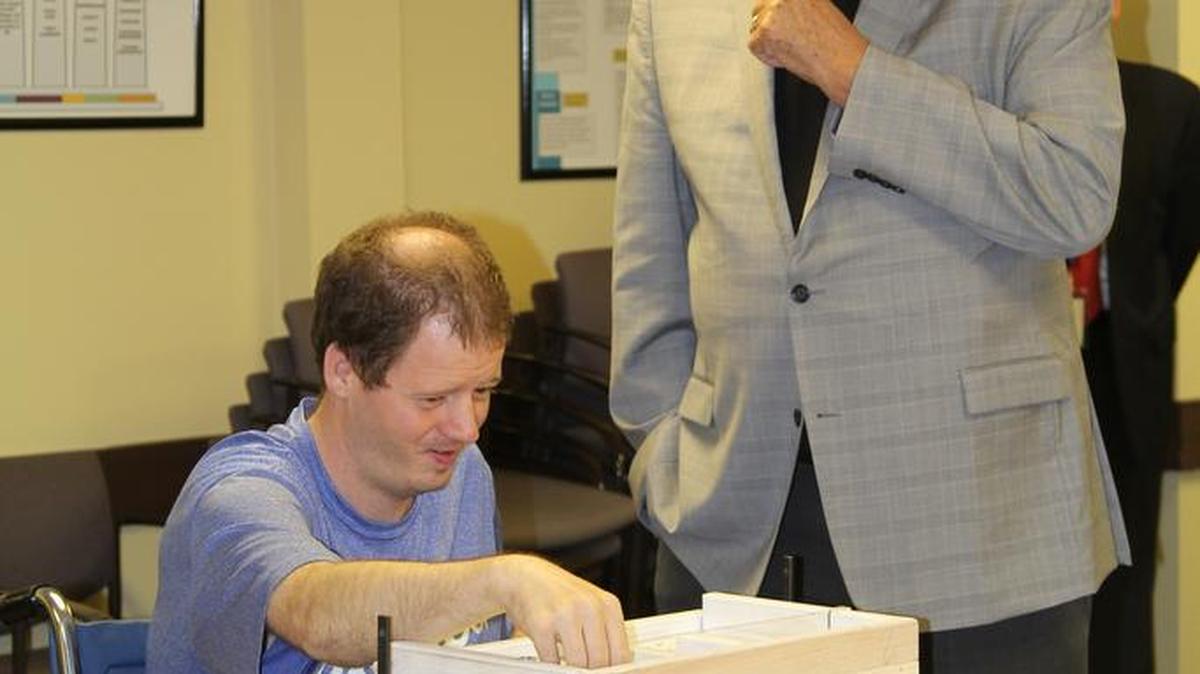 Johnson County Chairman Ed Eilert looked on recently as Johnson County Developmental Supports client Roy Brown used a counting and packaging system designed by the Gardner Edgerton High School Engineering Team.