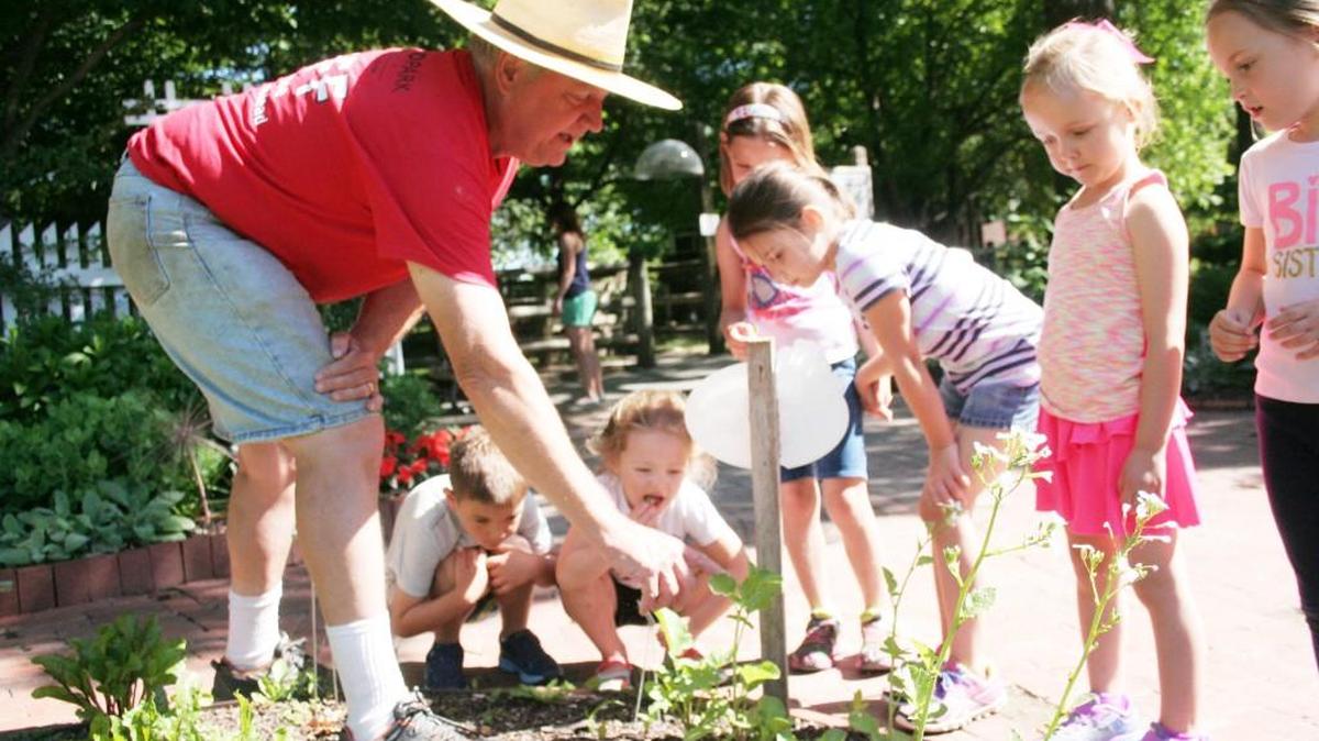 Olathe Master Gardener Miles Raymond teaches Mad Science Monday participants about plants in a garden at Deanna Rose Farmstead.