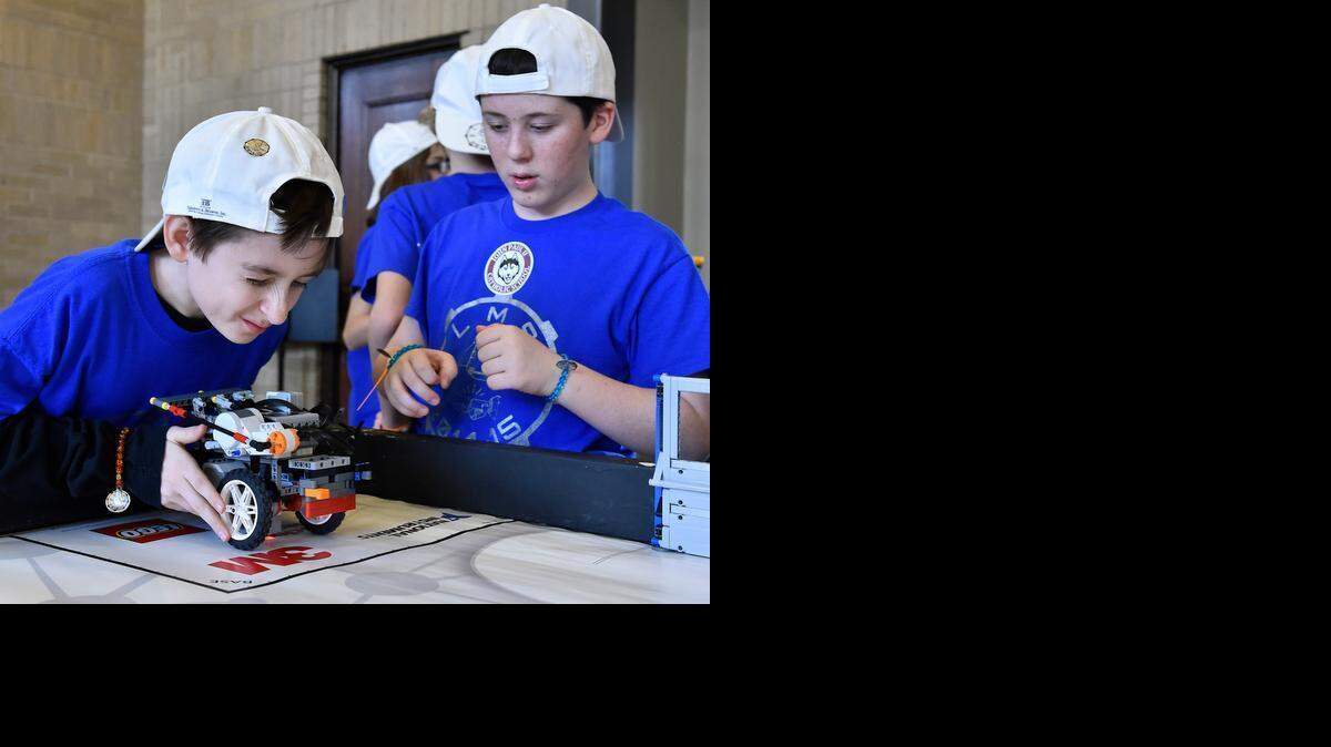 Will Laubscher (left) checked over his team’s robot before sending it on a mission. His Liberty Middle School seventh-grade classmate Connor Looney stood by at the FIRST Lego League Championship at Union Station recently.<252><137>Will Laubscher (left) closes one eye to check something out on the team robot before sending it on a mission. His Liberty Middle School seventh grade classmate Connor Looney stands by. Teams have two and a half minutes to complete as many missions as possible. Roughly 400 area students, from fourth through eighth grade, competed in the FIRST LEGO League Championship at Union Station Satuday, Jan. 17, 2015.<252><137>